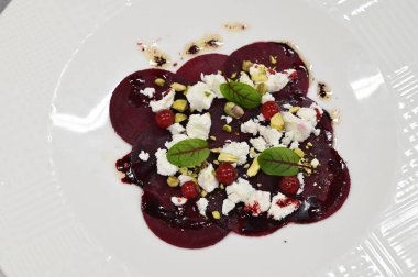Pancar carpaccio beyaz bir tabakta servis edilir, bir restoranda modern vejetaryen yemeğine yakın çekim, zarif bir yemek sunumu, sağlıklı gurme mutfağı,