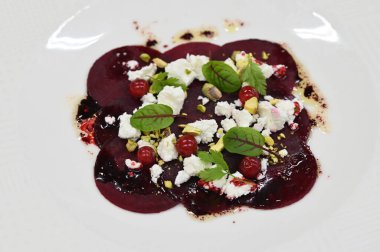 Pancar carpaccio beyaz bir tabakta servis edilir, bir restoranda modern vejetaryen yemeğine yakın çekim, zarif bir yemek sunumu, sağlıklı gurme mutfağı,