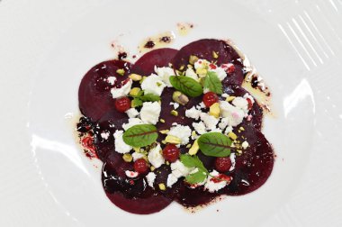 Pancar carpaccio beyaz bir tabakta servis edilir, bir restoranda modern vejetaryen yemeğine yakın çekim, zarif bir yemek sunumu, sağlıklı gurme mutfağı,