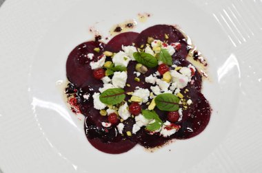Pancar carpaccio beyaz bir tabakta servis edilir, bir restoranda modern vejetaryen yemeğine yakın çekim, zarif bir yemek sunumu, sağlıklı gurme mutfağı,