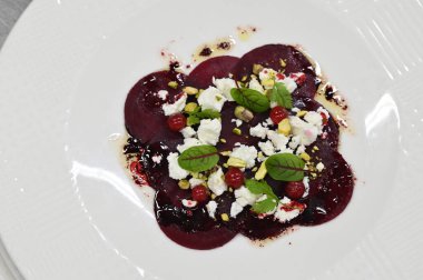 Pancar carpaccio beyaz bir tabakta servis edilir, bir restoranda modern vejetaryen yemeğine yakın çekim, zarif bir yemek sunumu, sağlıklı gurme mutfağı,