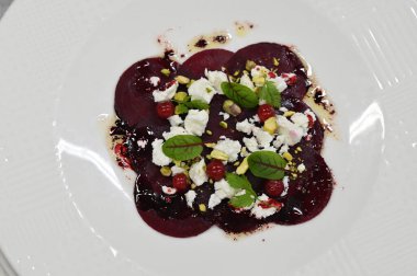 Pancar carpaccio beyaz bir tabakta servis edilir, bir restoranda modern vejetaryen yemeğine yakın çekim, zarif bir yemek sunumu, sağlıklı gurme mutfağı,