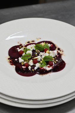 Pancar carpaccio beyaz bir tabakta servis edilir, bir restoranda modern vejetaryen yemeğine yakın çekim, zarif bir yemek sunumu, sağlıklı gurme mutfağı,