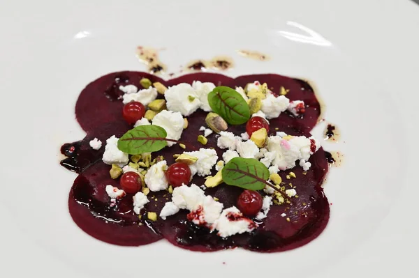Pancar carpaccio beyaz bir tabakta servis edilir, bir restoranda modern vejetaryen yemeğine yakın çekim, zarif bir yemek sunumu, sağlıklı gurme mutfağı,