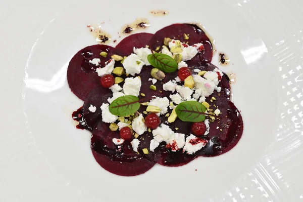 Pancar carpaccio beyaz bir tabakta servis edilir, bir restoranda modern vejetaryen yemeğine yakın çekim, zarif bir yemek sunumu, sağlıklı gurme mutfağı,