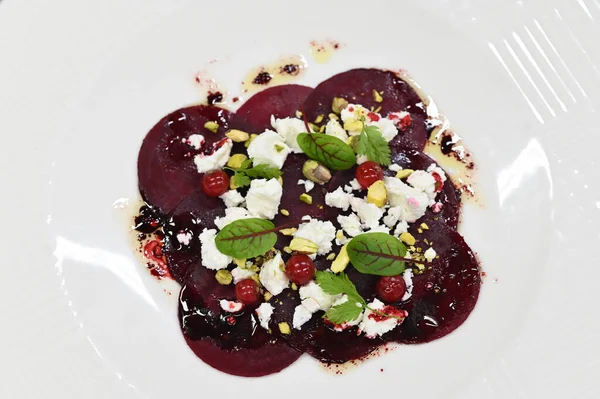 Pancar carpaccio beyaz bir tabakta servis edilir, bir restoranda modern vejetaryen yemeğine yakın çekim, zarif bir yemek sunumu, sağlıklı gurme mutfağı,