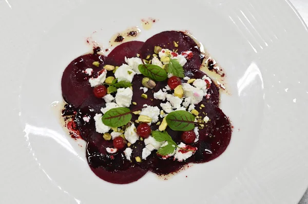 Pancar carpaccio beyaz bir tabakta servis edilir, bir restoranda modern vejetaryen yemeğine yakın çekim, zarif bir yemek sunumu, sağlıklı gurme mutfağı,