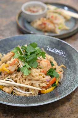 Karidesli erişte ve siyah bir tabakta sebze.