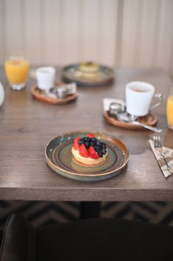 Lezzetli taze meyveli kek beyaz bir tabakta bir restoranda beyaz ahşap bir masada..