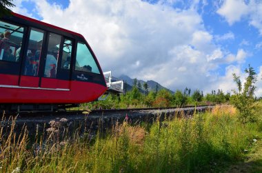 High Tatras 'ın panoramik manzaralı Star Smokovec' teki raylı demiryolu ve dağ treni. Görüntü, Tatras 'ın göbeğinde Slovakya' daki dağ manzarası ve manzaralı dağ zirveleriyle çevrili geleneksel dağ ulaşımını yakalıyor..