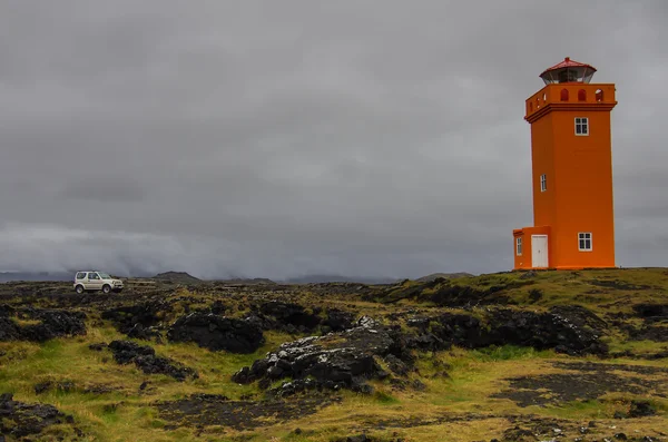 L'auto di fronte al faro arancione sulle rocce in Islanda — Foto Stock