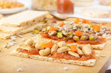 İnce bir tabaka kayısı reçeli ve ahşap bir tahta üzerinde doğu tatlılarının arka planına karşı fıstık, fıstık, kuru üzüm ve şekerli gevrek, düşük kalorili kraker. Yakın plan.