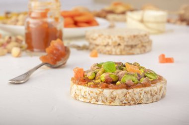 Patlamış buğday taneleri şam fıstıklı ve şekerli meyveler ince bir tabaka kayısı reçeli beyaz ahşap bir masada doğu tatlılarının arka planında