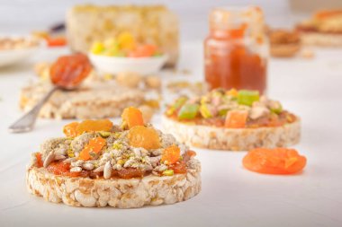 Patlamış buğday taneleri, kabuğu soyulmuş ayçiçeği çekirdekleri, yarım ve kuru üzümler beyaz ahşap bir masa üzerinde doğu tatlılarının arka planında ince bir tabaka kayısı reçeli üzerinde.