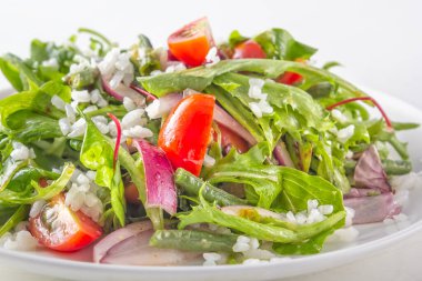 Yeşiller, domates ve roka, yeşil bezelye ve kırmızı soğanlı pirinç salatası. Yakın plan.