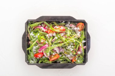 Bitki salatası, domates ve roka, yeşil bezelye ve kırmızı soğanlı pilav. Beyaz arka planda tek kullanımlık kağıt bir kutuda. Yemek teslimatı konsepti. Sağlıklı beslenme. Üst görünüm