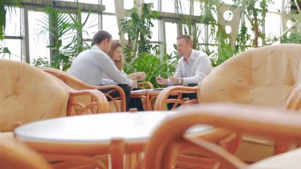 Två affärsmän och affärskvinna sitta vid ett bord i lilla cafeteria — Stockvideo