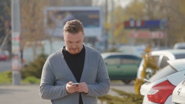 El joven va en el estacionamiento y pulgares a través de una transmisión de noticias en Internet — Vídeos de Stock