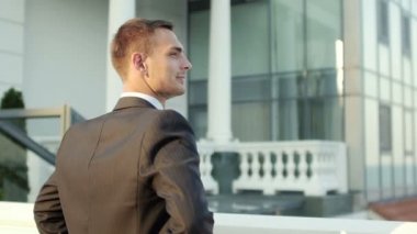 Young successful businessman standing near office building and smiling