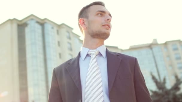 Jeune homme d'affaires prospère debout près de l'immeuble de bureaux et souriant — Video