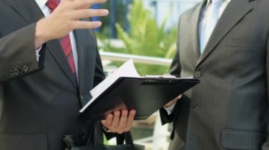 iş adamları bir ofis binasının yanında ayakta