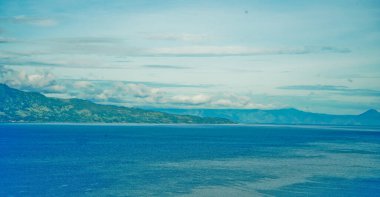 Yeşil tepeler ve açık gökyüzüyle gölün güzel manzarası.