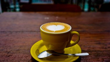 Kahverengi bir masanın üzerindeki bir fincan kahvenin fotoğrafını çek.