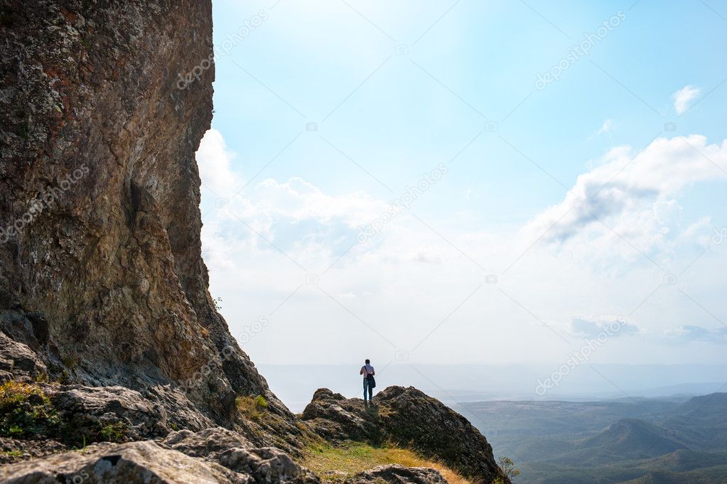 man on the edge of a cliff in the mountains