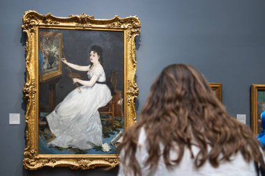 Ulusal Galeri 'de çerçeveli bir başyapıta hayran olan bir kadının arka planı. Londra, İngiltere, 28 Haziran 2023