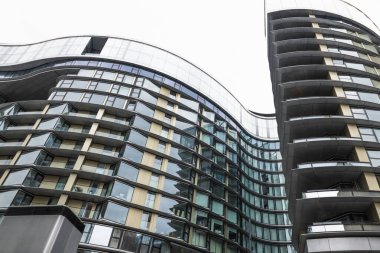 Kavisli cam cepheli ve istiflenmiş balkonlu modern apartman kulelerinin yukarıdan görünüşü.