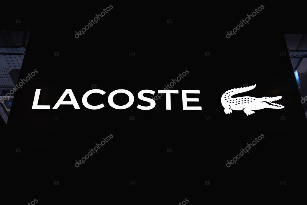 Close view of Lacoste store signage at night, bold white logotype and crocodile symbol. London, UK, 4 July 2023