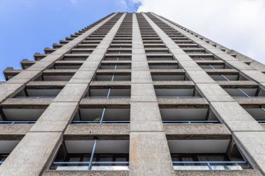Londra 'daki Barbican Konutları' nın düşük açılı çekimleri, barbar beton dokusunu gözler önüne seriyor, parlak gökyüzüne karşı balkonları ve ızgara geometrisini tekrarlıyor..
