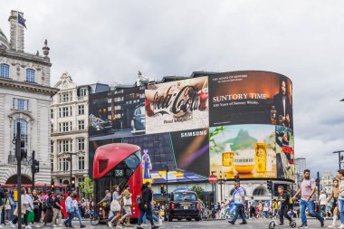 Londra 'nın merkezindeki Piccadilly Sirki' nin canlı görüntüsü dijital reklam panoları, kırmızı çift katlı bir otobüs, kalabalık kalabalık ve West End 'deki tarihi mimari. Londra, İngiltere, 16 Temmuz 2023