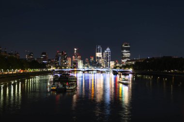 Londons South Bank ve Thames 'in gece görüşü, parlayan şehir ışıkları, aydınlık köprüler ve pürüzsüz su yansımaları. Londra, İngiltere, 22 Temmuz 2023