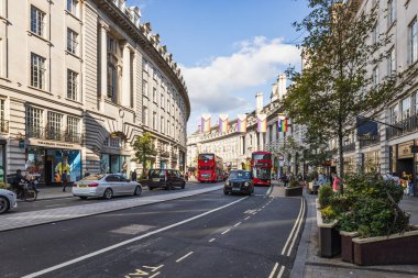 Londons West End 'deki canlı Regent Caddesi manzarası kırmızı çift katlı, siyah taksisi, tarihi cepheleri, işlek dükkanları ve mavi gökyüzü günüyle. Londra, İngiltere, 23 Temmuz 2023