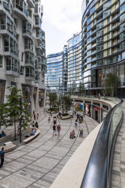 Londra 'nın Battersea kentindeki modern apartman kuleleri arasında, yaya dostu bir şehir sahnesinde dükkanlar, kafeler ve yeşillikler arasında canlı bir yürüyüş. Londra, İngiltere, 29 Temmuz 2023