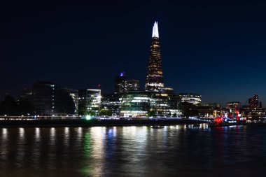 Thames Nehri 'ndeki Çömlek ve Londons South Bank' ın gece manzarası. Parlayan şehir ışıkları ve pürüzsüz su yansımaları modern bir şehir silüeti oluşturuyor..