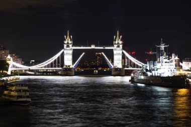 Aydınlatılmış Kule Köprüsü geceleri Thames Nehri 'ni HMS Belfast ile kaplar. Londra, İngiltere, 27 Ağustos 2023