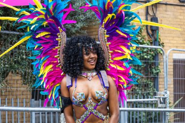 2023 Notting Hill Karnavalı sırasında mücevherli kostüm ve tüylü kanatlar içinde gülümseyen bir gösteri sanatçısı. Londra, İngiltere, 28 Ağustos 2023