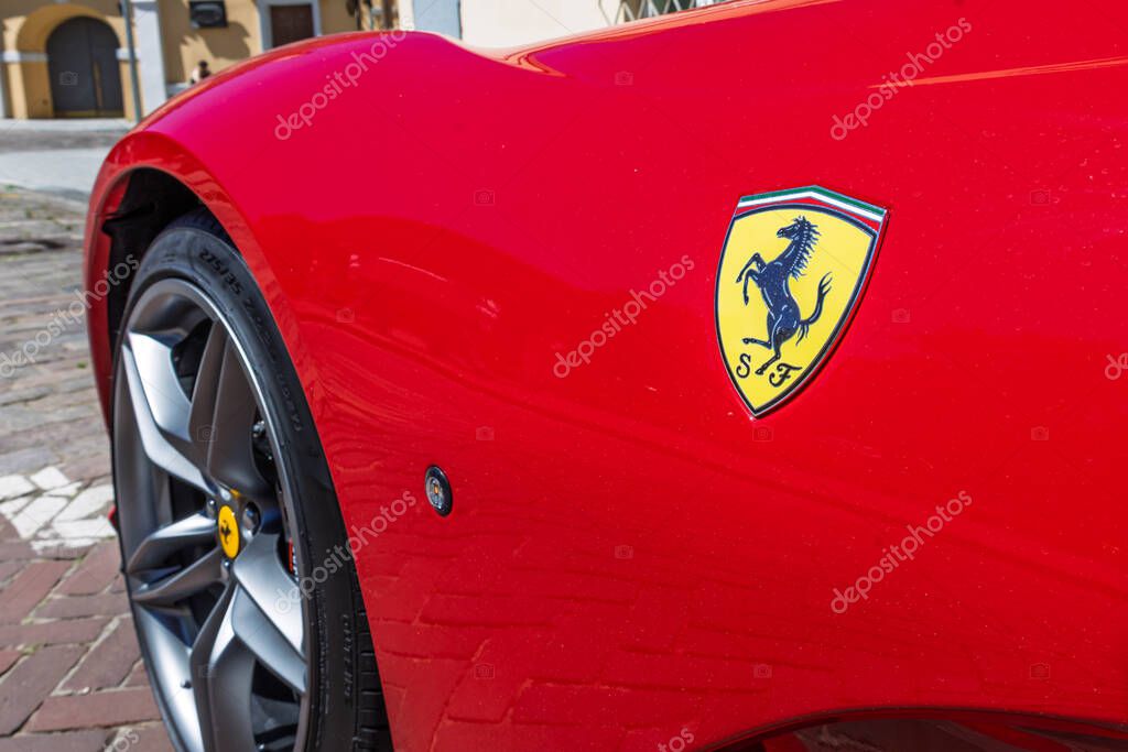 Macro view of Ferrari badge on red body panel with alloy wheel visible. Vilnius, Lithuania, 2 July 2025