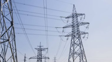 Çelik sütunlar ve yüksek gerilim hatları gökyüzünü kaplar..