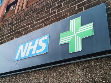 Dışında yeşil haç olan NHS eczane işaretini kapat. Londra, İngiltere, 15 Nisan 2024