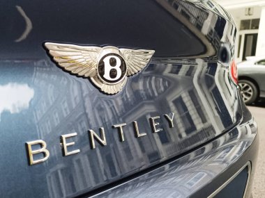 B kanatlı Bentley 'lerin makro çekimi ve mavi boya üzerine harfler, şehir mimarisini yansıtan krom detaylar. Londra, İngiltere, 25 Nisan 2024