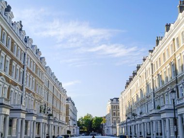 Klasik Londra sokaklarının beyaz sıva terasları, mükemmel simetri ve parlak mavi gökyüzünün altındaki güçlü kaybolma noktası..