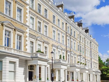 Londra 'da beyaz sıva, koyu pencereli ve mavi gökyüzünün altındaki sütunlu Viktorya döneminden kalma zarif teraslı evler..