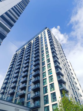 Camları ve balkonları olan modern bir apartman manzarası..