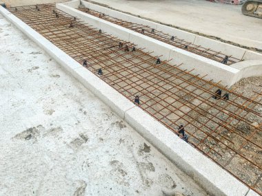 İnşaat sahasında demirle örülmüş beton döşemeye hazır adımlar ve yürüyüş için. Görünür boşluklar, hizalanmış şebeke ve hazırlanmış temel.
