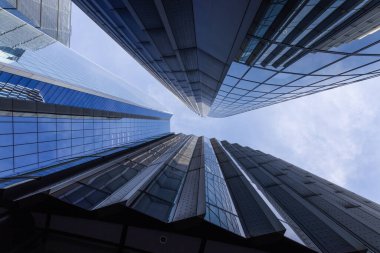 Geometrik bir ufuk çizgisi oluşturan yansıtıcı gökdelenlerin dramatik alçak açılı görüntüsü.