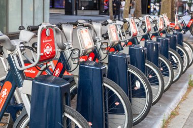 Londra bisiklet paylaşım istasyonu. Birden fazla kırmızı motosiklet kiralayanlar ve ziyaretçiler için hazır. Londra, İngiltere, 2 Eylül 2023