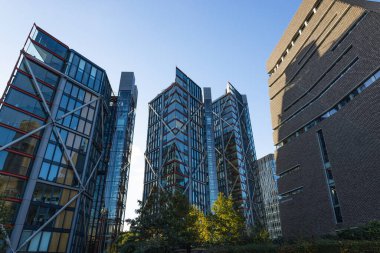 Göze çarpan modern mimari. Açık mavi gökdelenler altında cam kaplı gökdelenler.